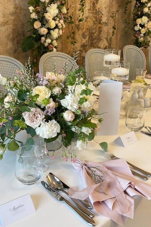 Różowe serwety na przyjęciu weselnym i niskie kompozycje kwiatowe w kolorach pastelowych