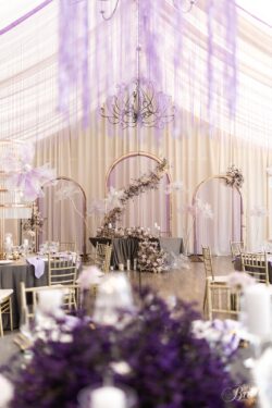 Złote łuki za stołem prezydialnym z girlandą kwiatową.